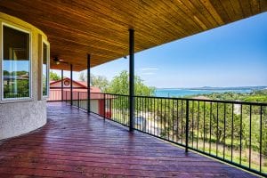 Covered rental house balcony with rod iron railing, and beautiful water view of the lake